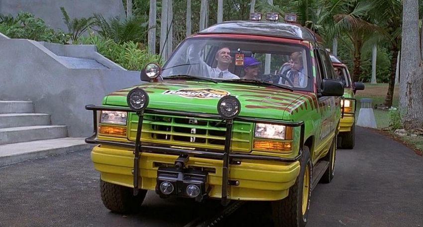 A scene from the movie, showing three characters inside the car clearly impressed by the technology behind it, while the man in the front sets everything up before a ride.