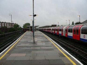 A westbound platform view, a thin platform isle surrounded by rails. Plenty of open space around.