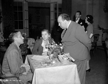 Hitchcock, Laurence Olivier and Joan Fontaine by the table, Hitch and Olivier staring at each other.