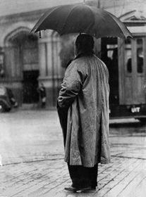 Hitch standing in the rain, with his back to the camera.