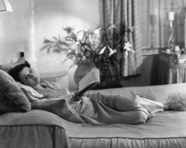 Young Vivien Leigh lying in her bed and reading a book.